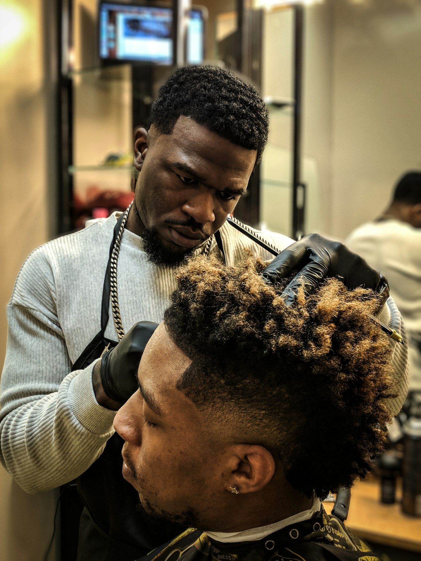 A barber working through a client's hair with scissors and comb