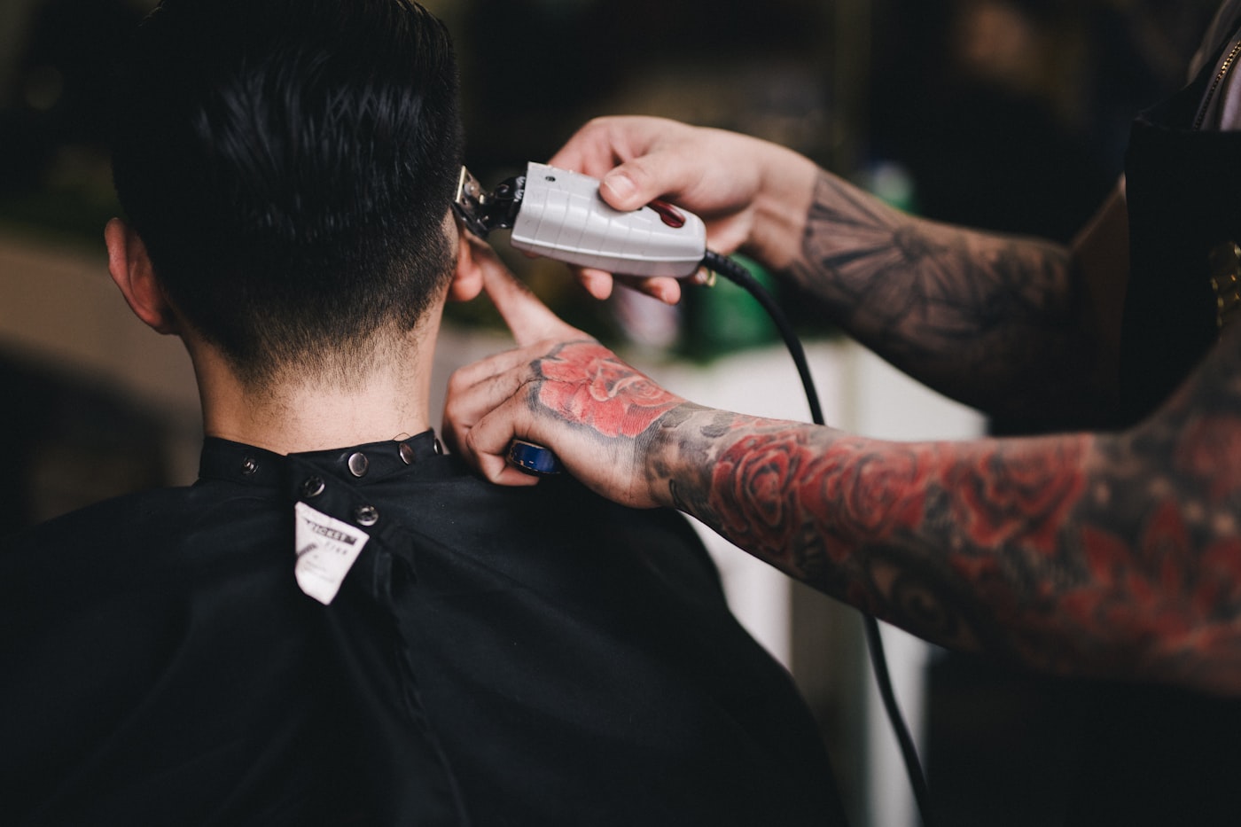 Close view of clippers cutting a tight fade into dark hair
