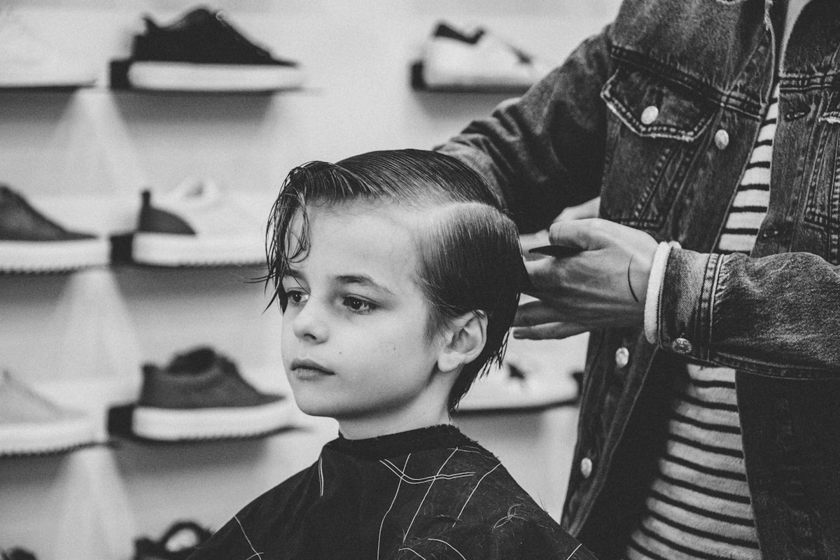 A young boy having his hair cut in a barber chair