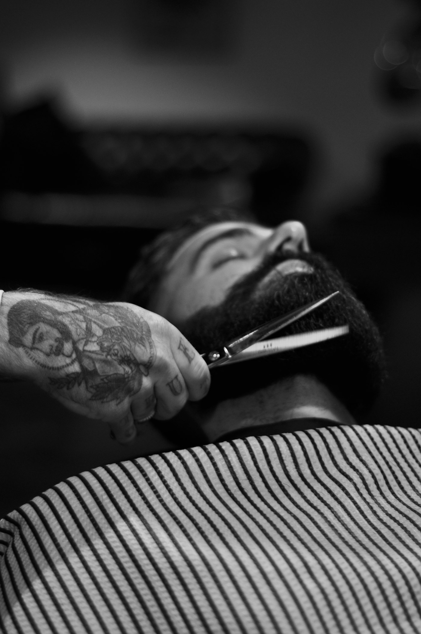 Black and white photograph of a man reclined in a barber chair mid-shave